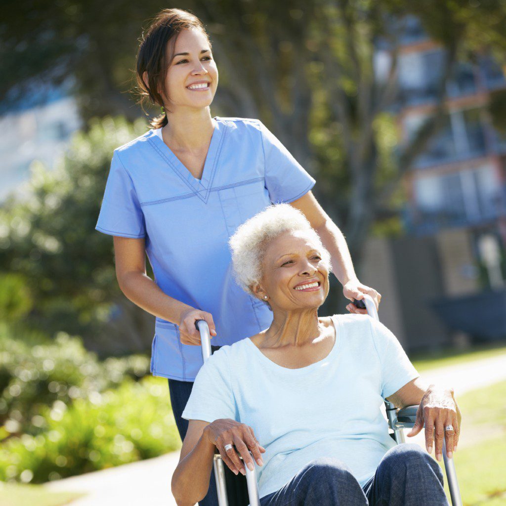 Carer Pushing Senior Woman In Wheelchair