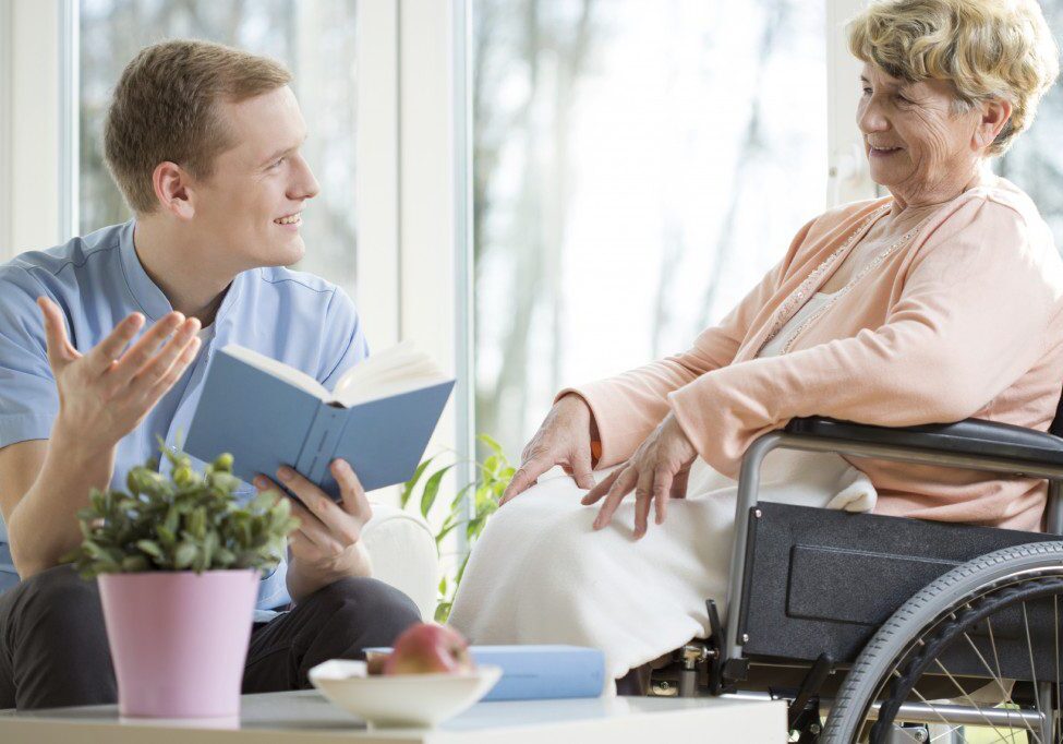 Caregiver reading to senior woman at home